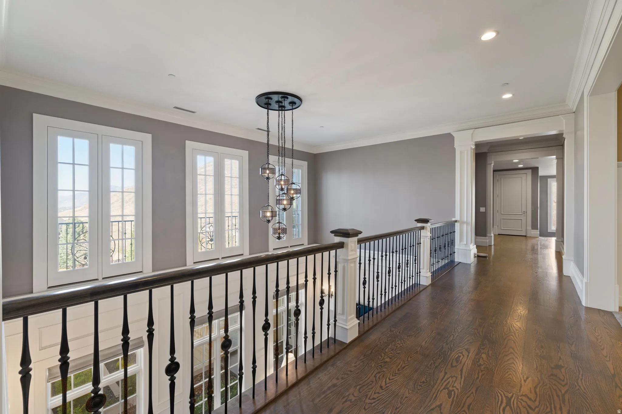 Corridor featuring dark wood-style flooring, crown molding, and hanging lights