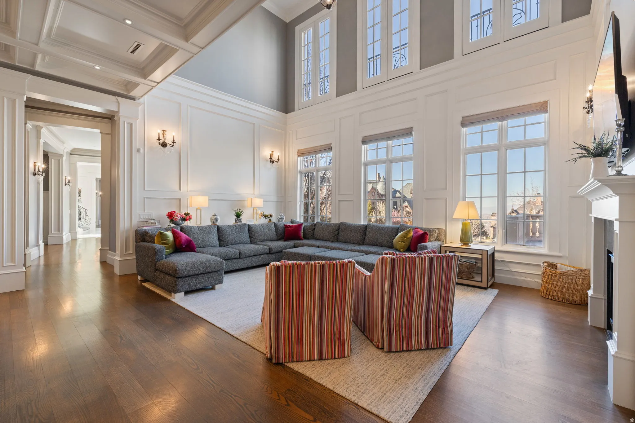Living room with a decorative wall, hardwood / wood-style floors, a fireplace, high coffered ceiling, and crown molding