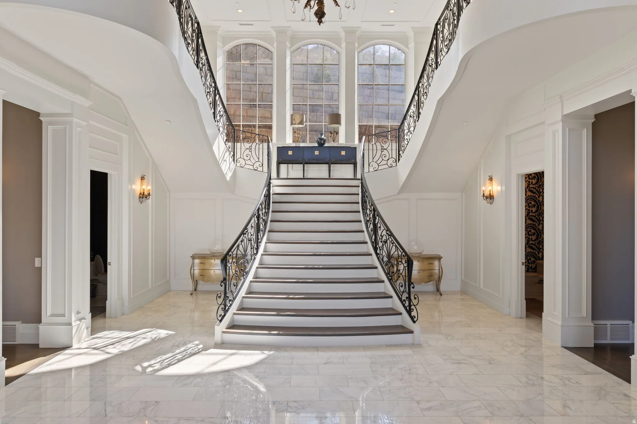 Staircase featuring decorative columns, a decorative wall, marble tiled floors, healthy amount of natural light, and a high ceiling