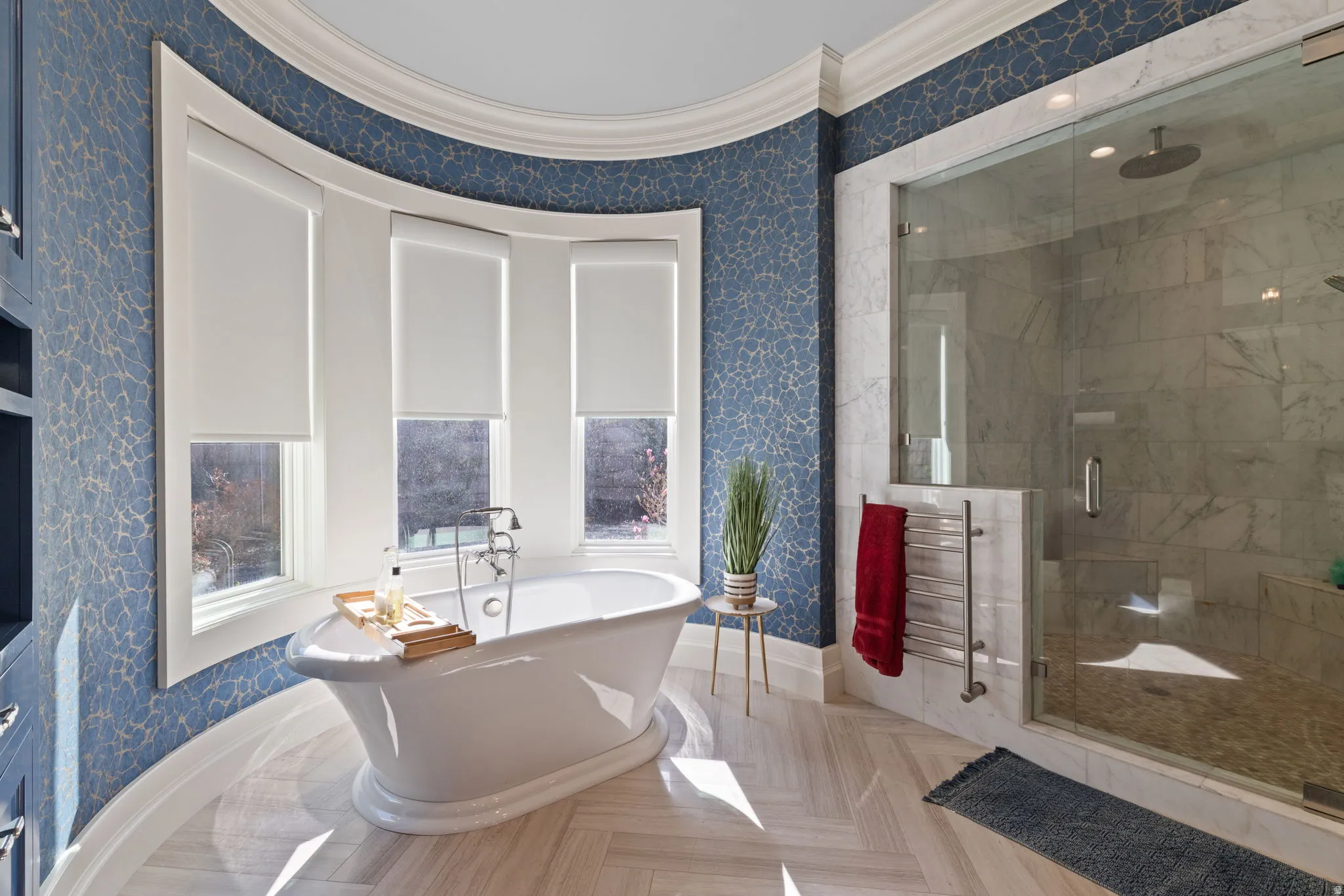 Bathroom with wallpapered walls, ornamental molding, a freestanding tub, a shower stall, and a towel warmer
