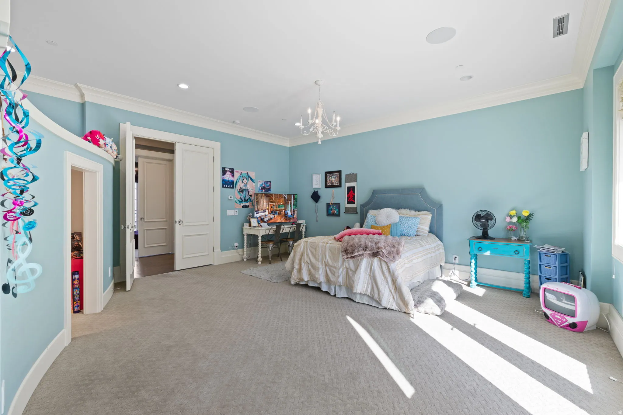 Bedroom featuring ornamental molding, light colored carpet, and hanging lights