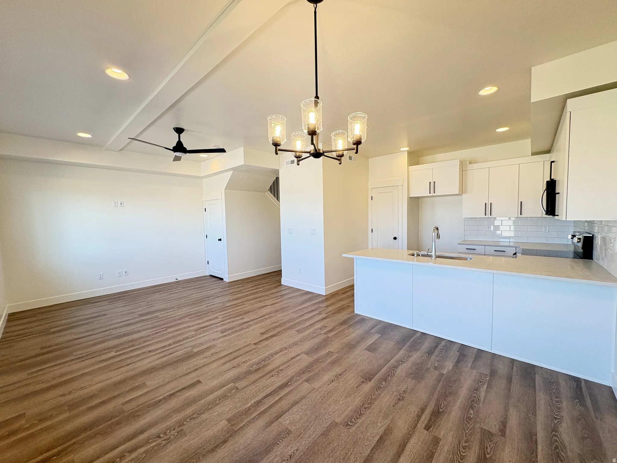 Kitchen with hanging lights, white cabinetry, tasteful backsplash, dark wood-type flooring, and open floor plan