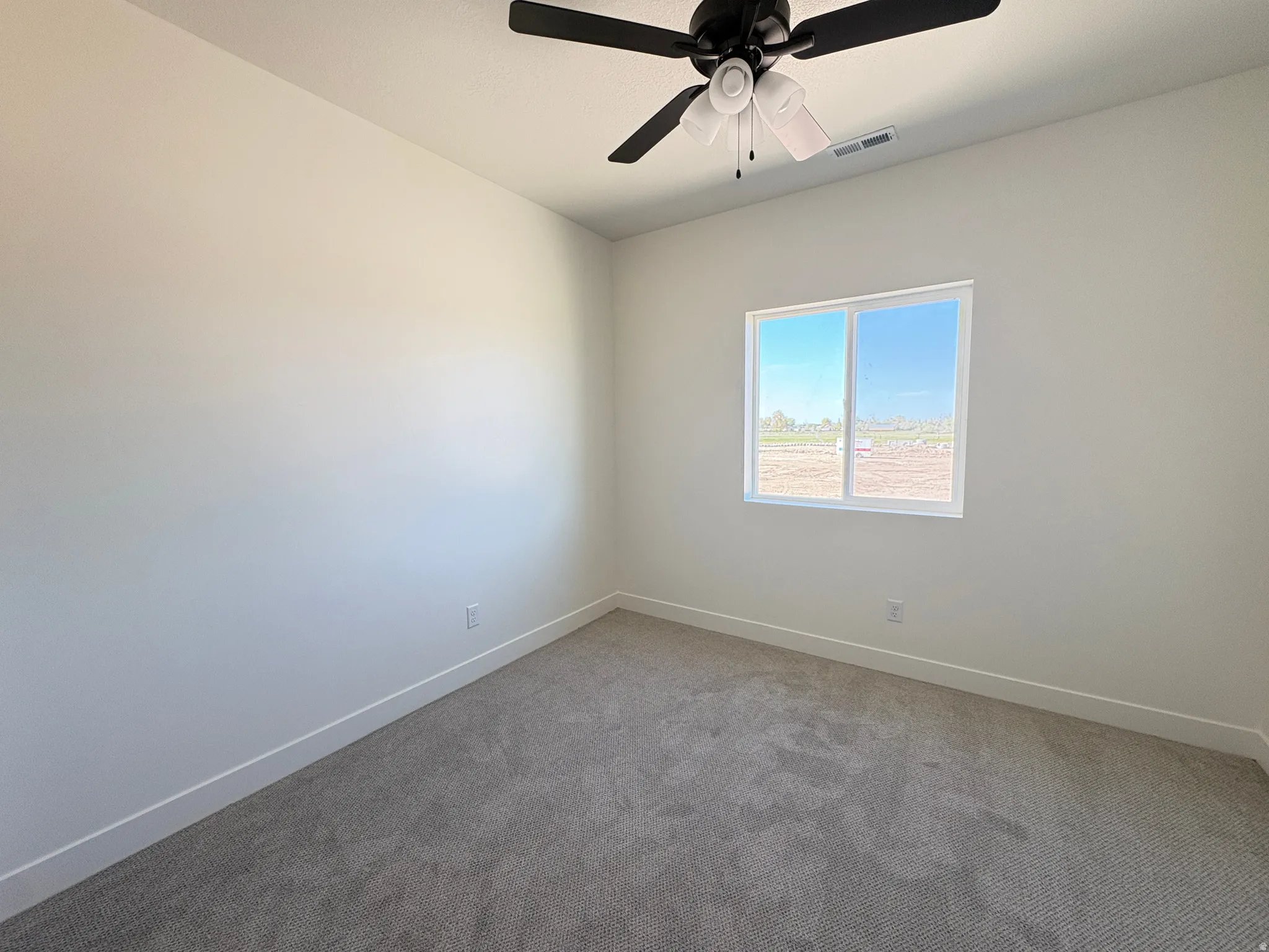 Carpeted empty room with a ceiling fan and baseboards