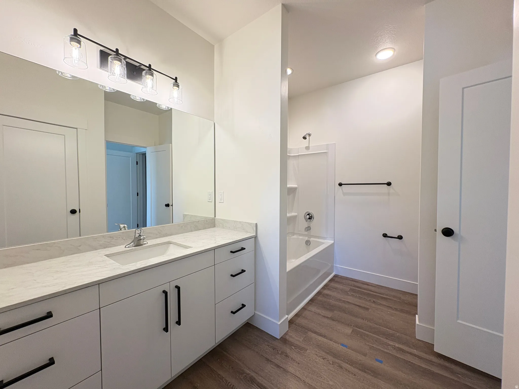 Full bathroom with vanity, dark wood-style floors, and shower / bathtub combination