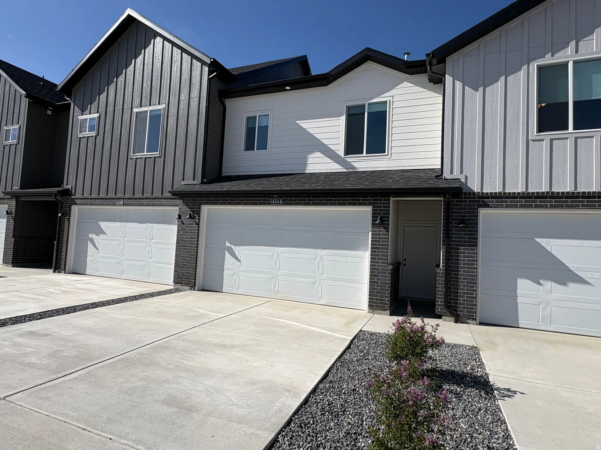 View of front of property with brick siding, board and batten siding, an attached garage, and concrete driveway