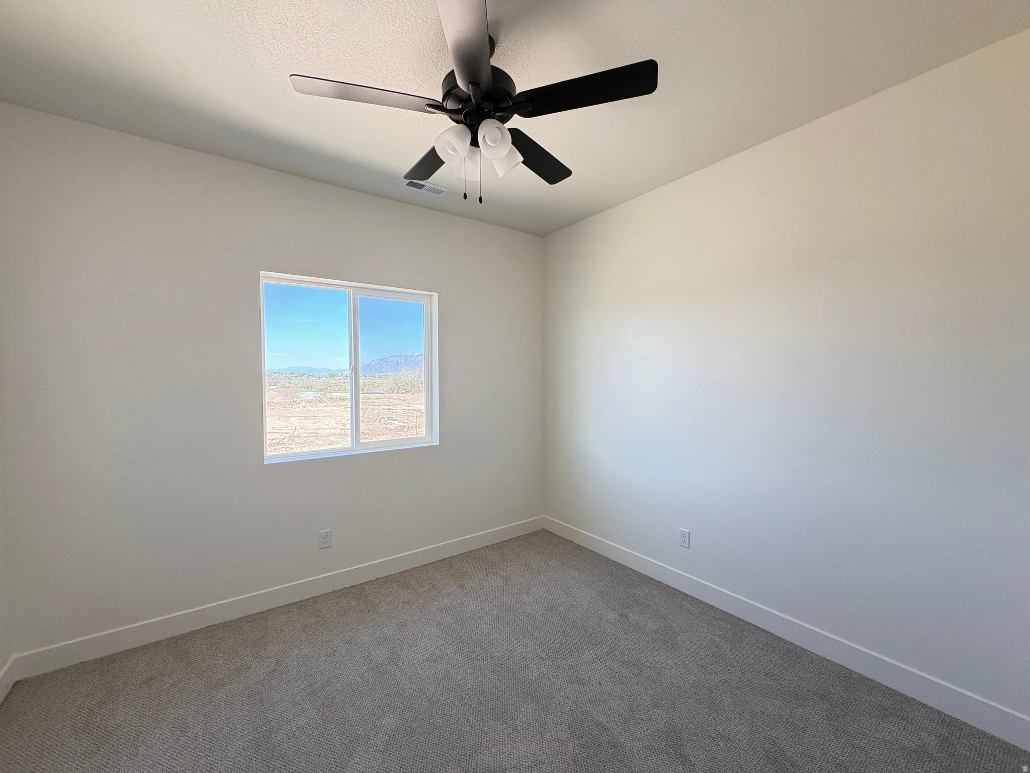 Carpeted empty room featuring baseboards and a ceiling fan