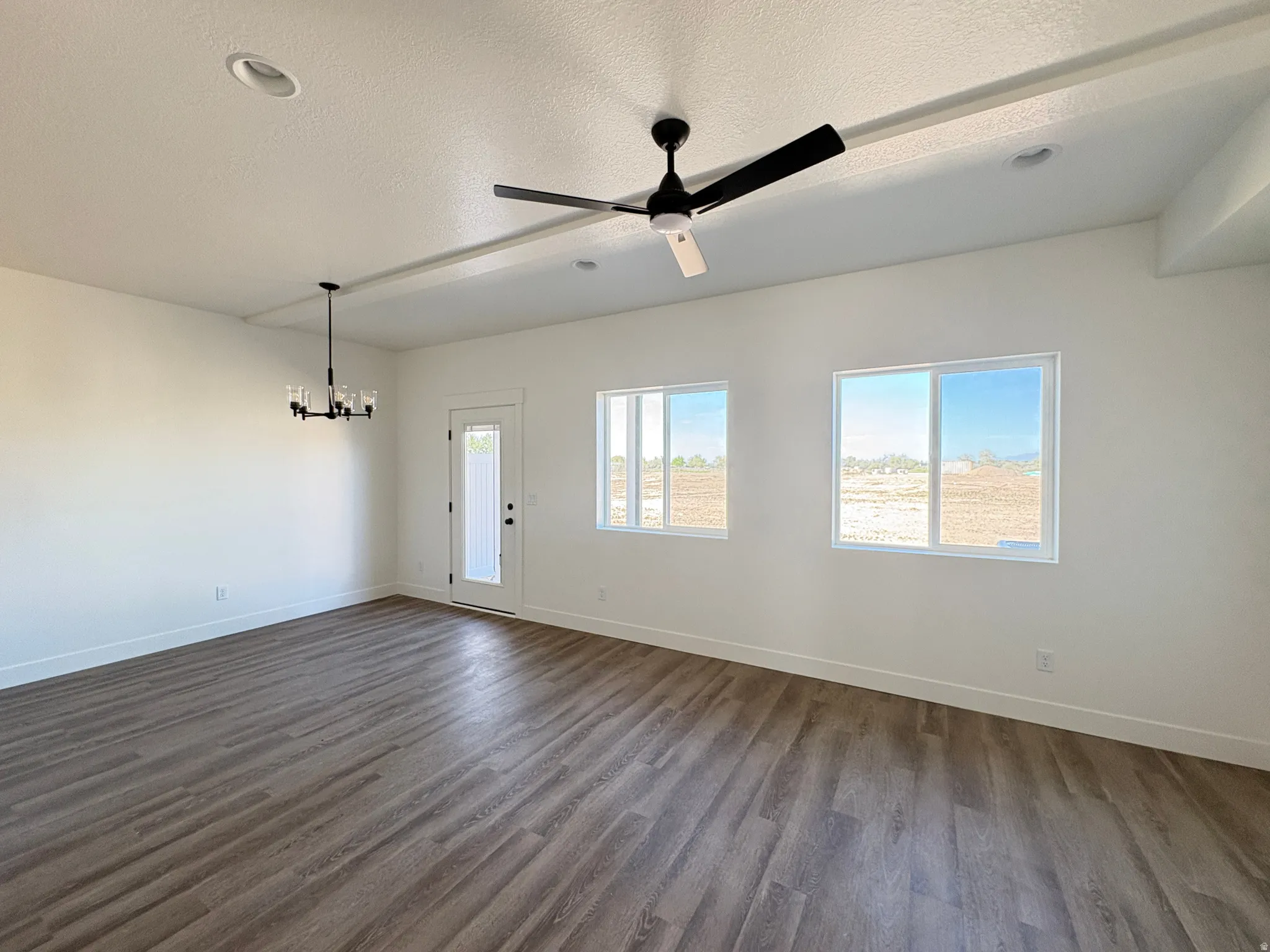 Entryway featuring ceiling fan, dark wood-style flooring, a textured ceiling, and a chandelier
