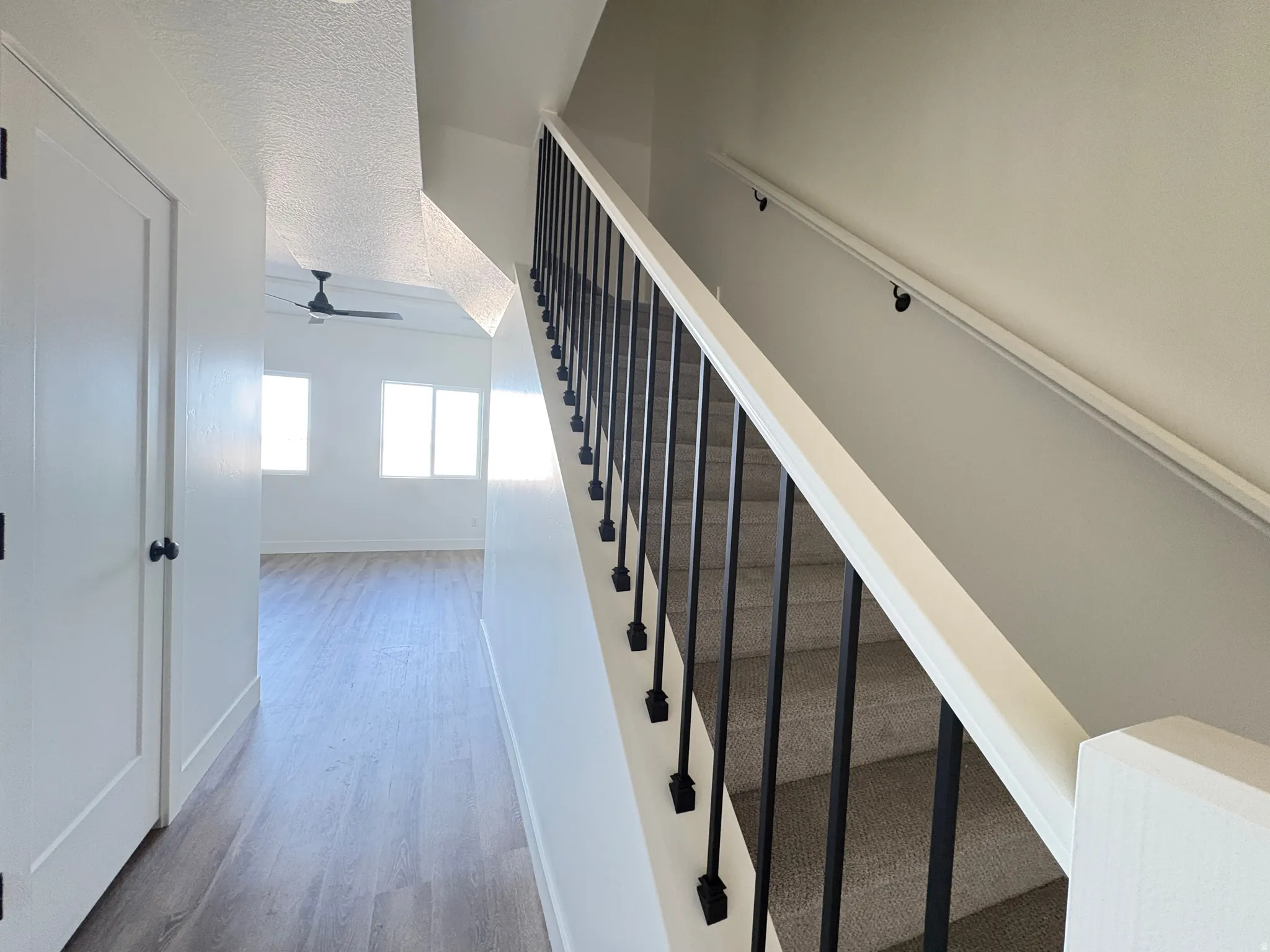 Stairs with a ceiling fan, wood finished floors, and a textured ceiling
