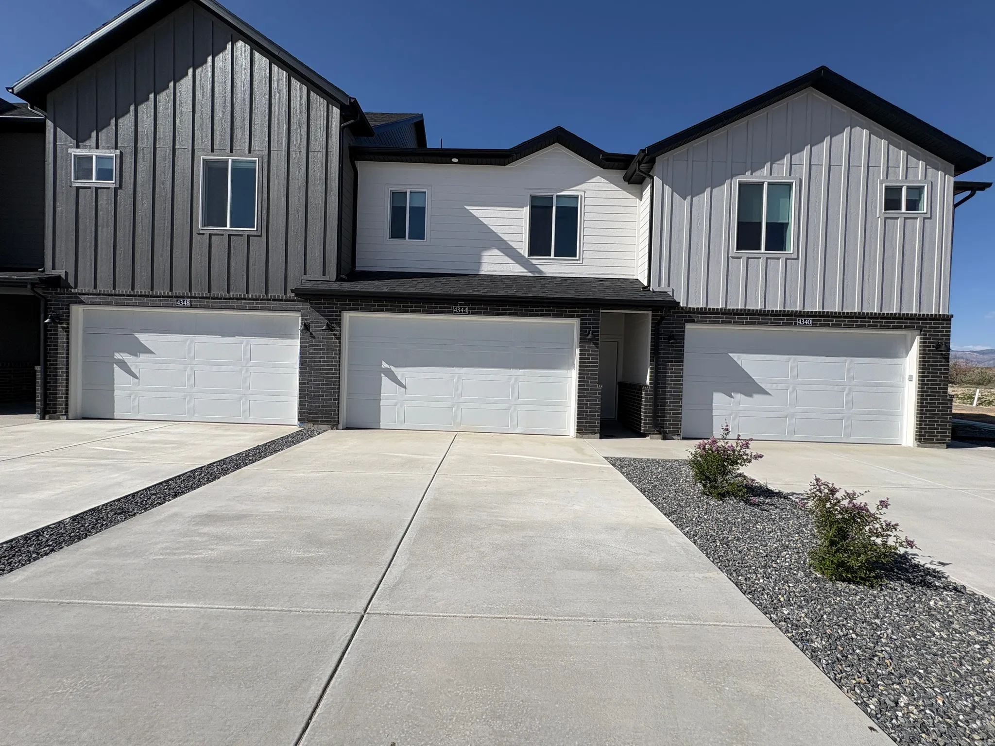View of front of house with board and batten siding, a garage, and brick siding