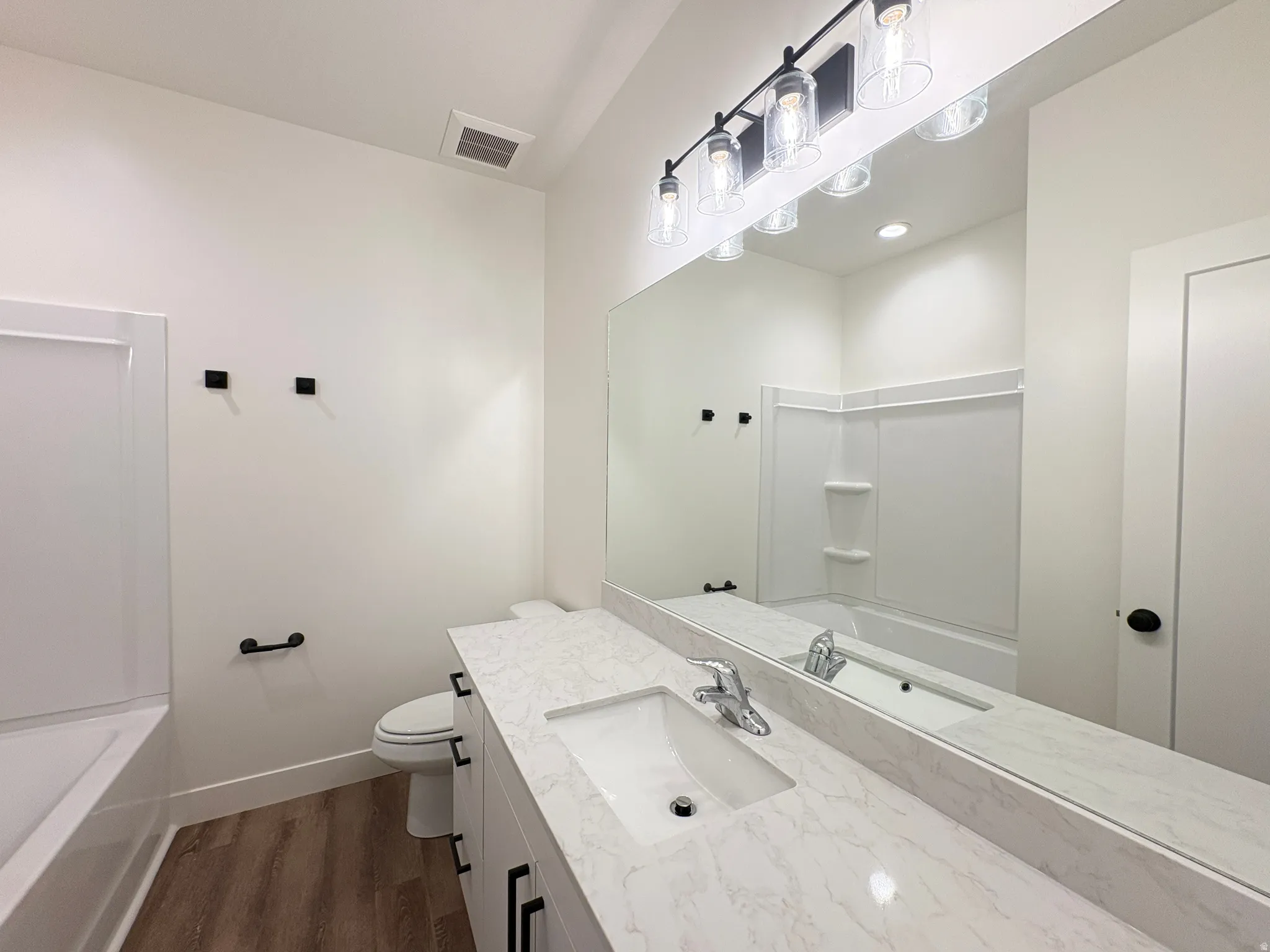 Bathroom with shower / washtub combination, vanity, and dark wood-type flooring