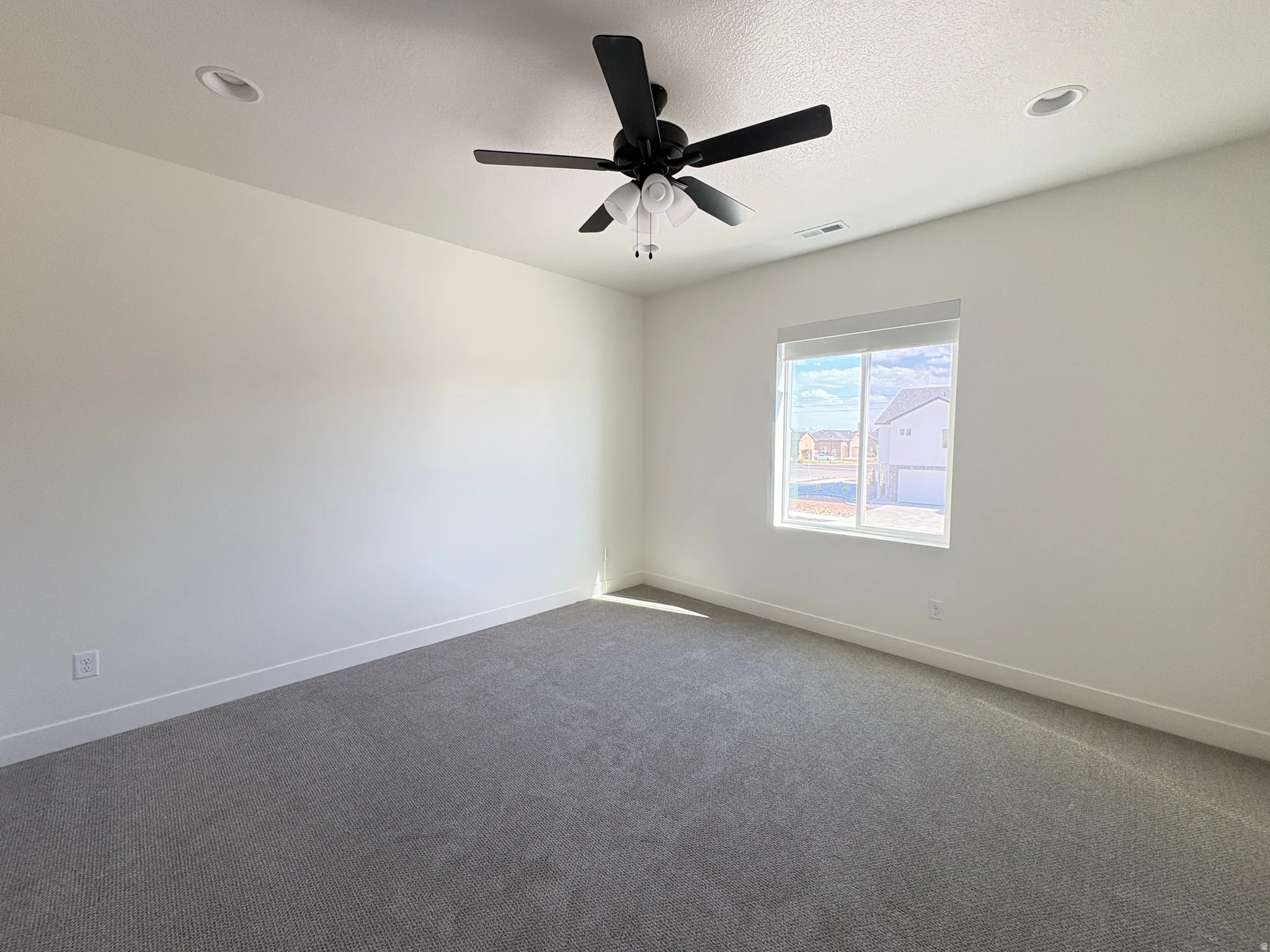 Unfurnished room with dark colored carpet and ceiling fan