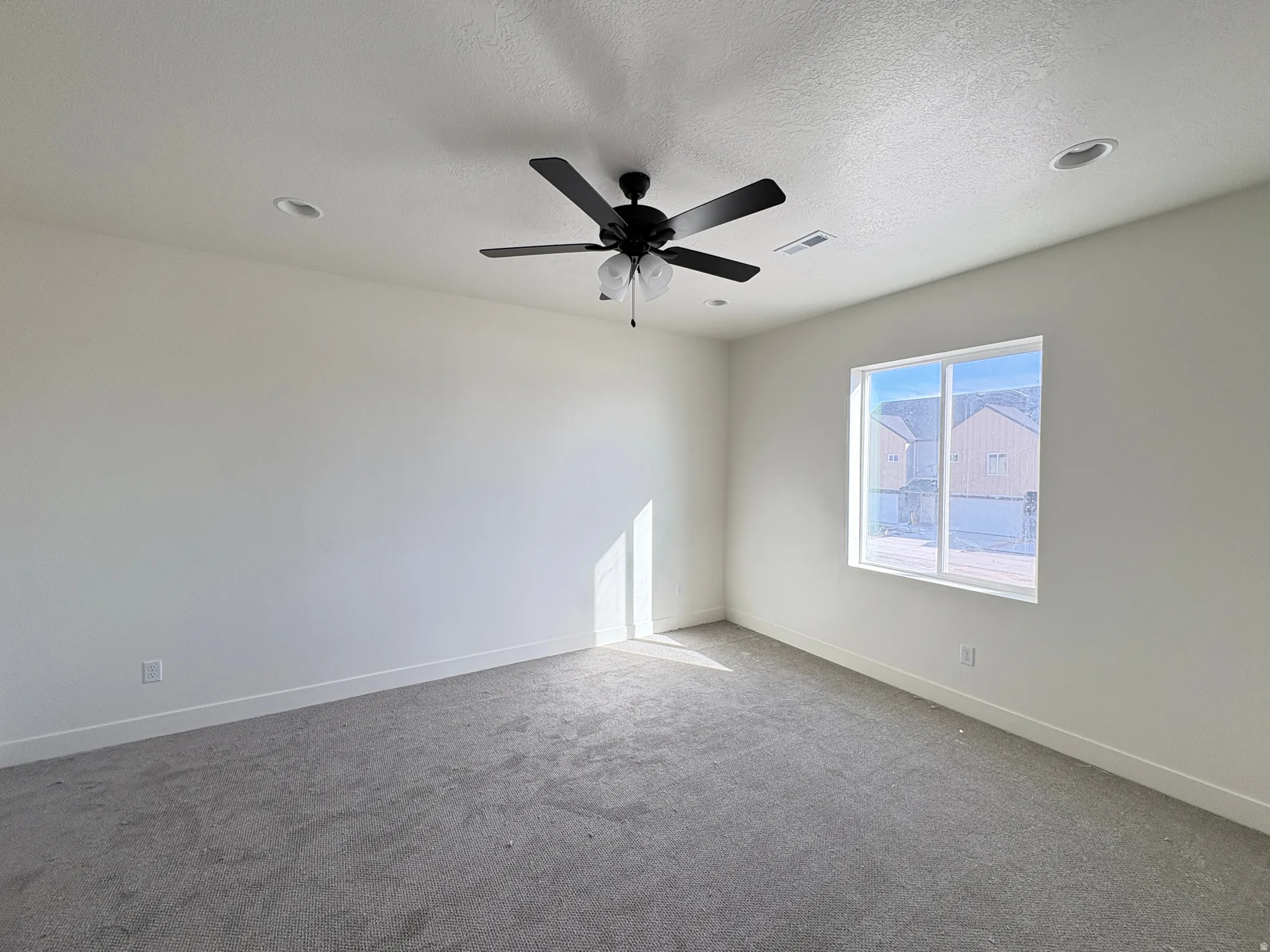 Carpeted spare room with a textured ceiling and a ceiling fan