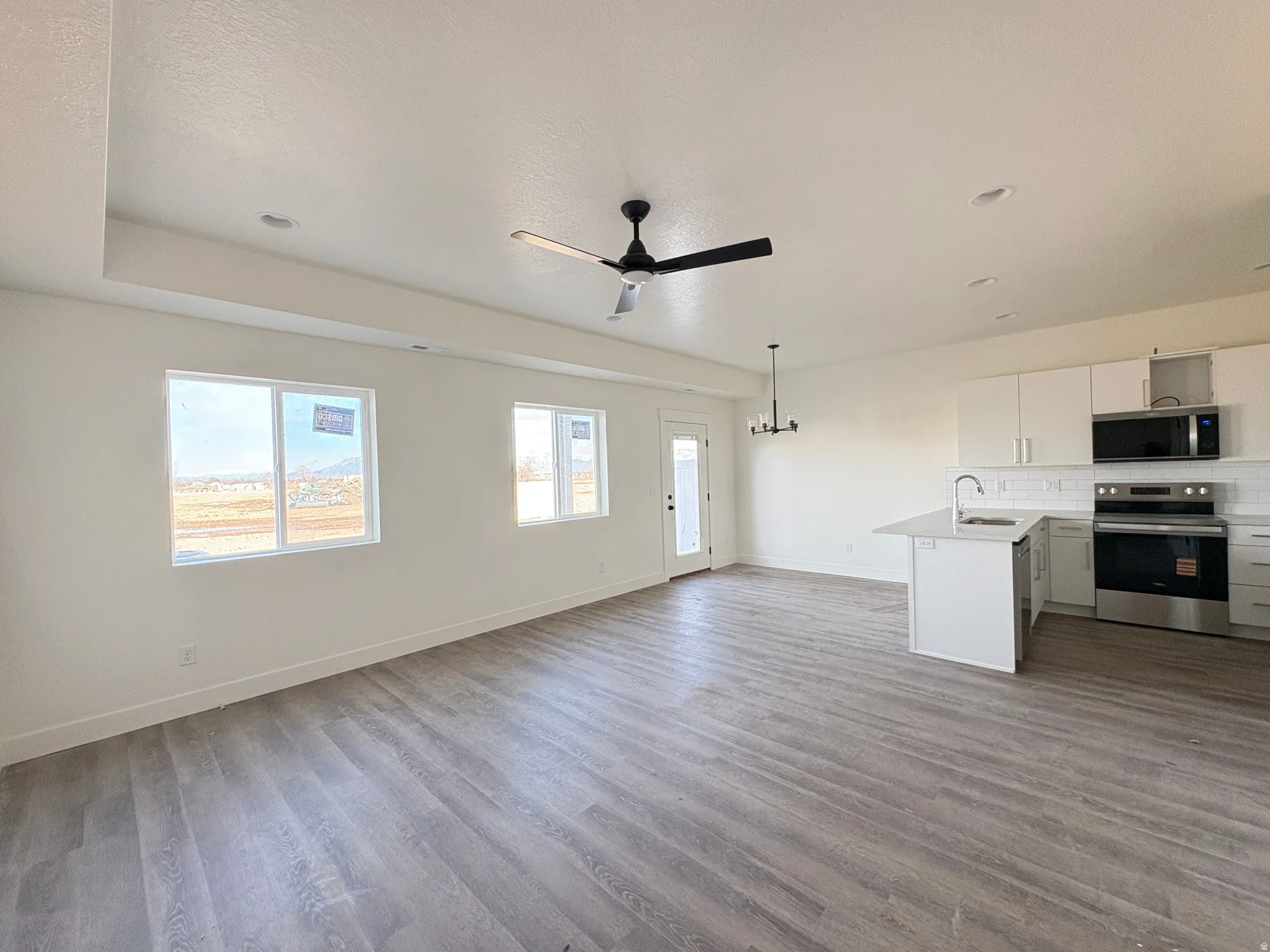 Unfurnished living room with light wood-style floors, ceiling fan, and a chandelier