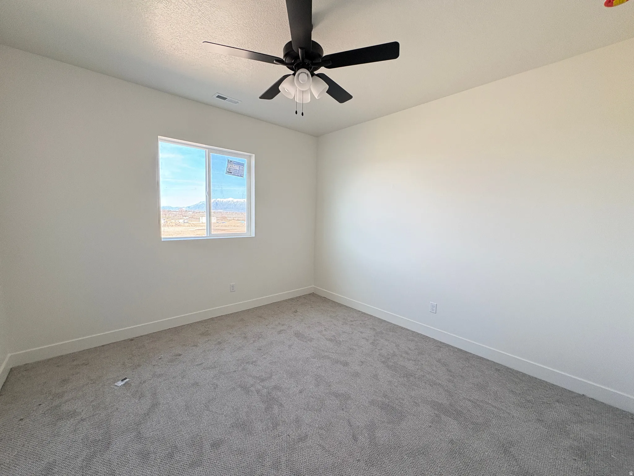 Carpeted empty room featuring baseboards and ceiling fan