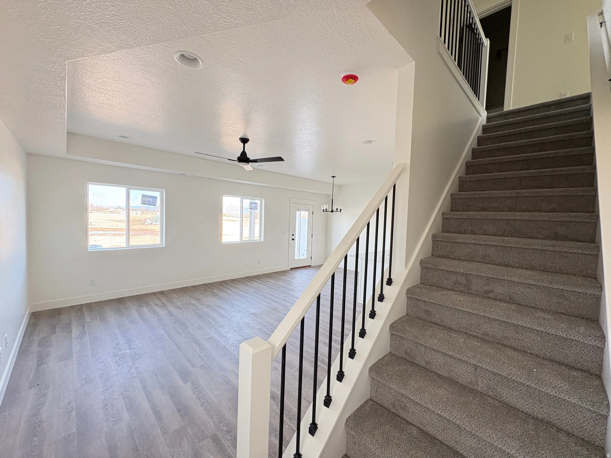 Stairs with a textured ceiling, wood finished floors, and ceiling fan