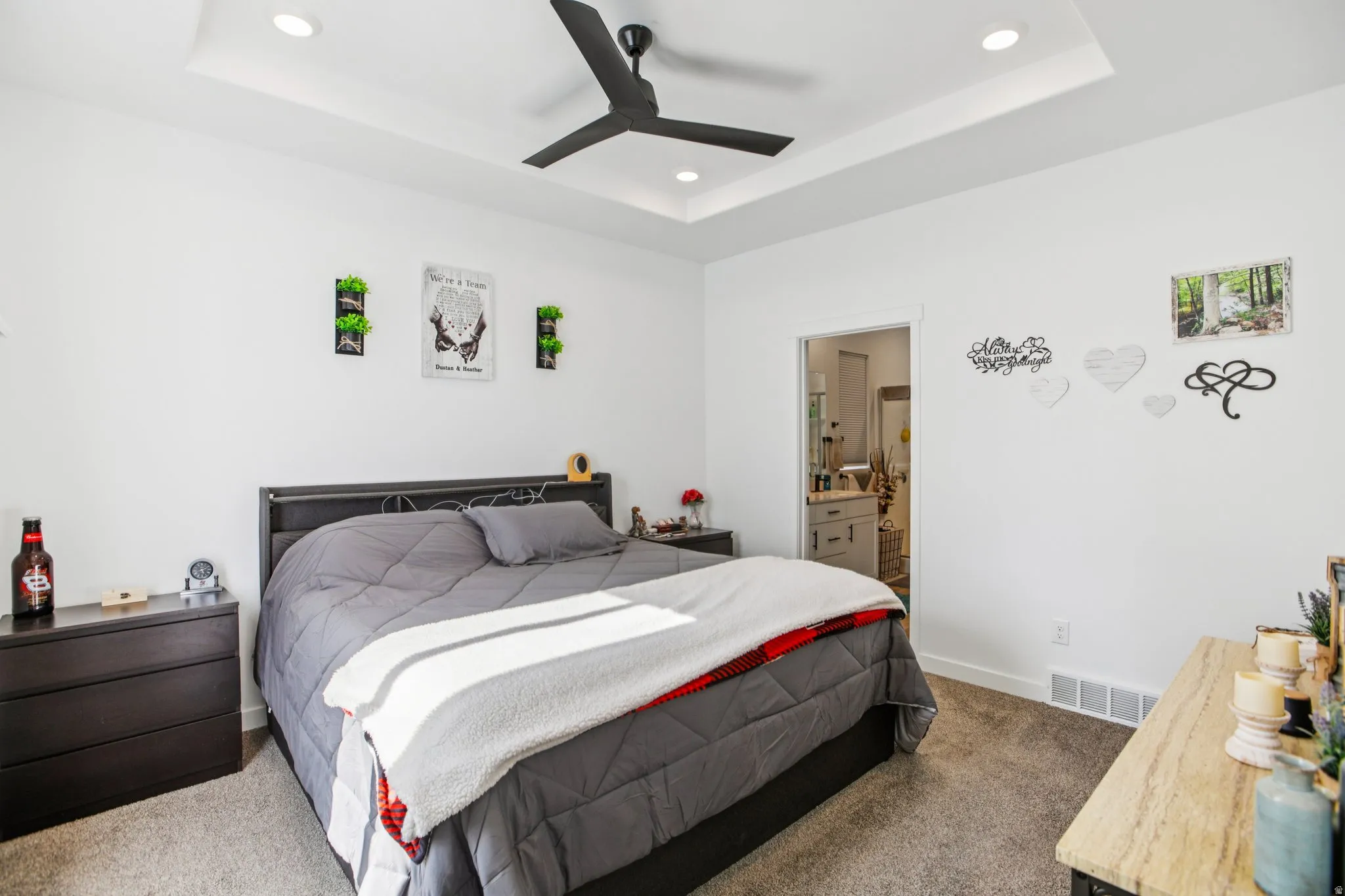 Bedroom featuring dark colored carpet, recessed lighting, a ceiling fan, ensuite bathroom, and a tray ceiling