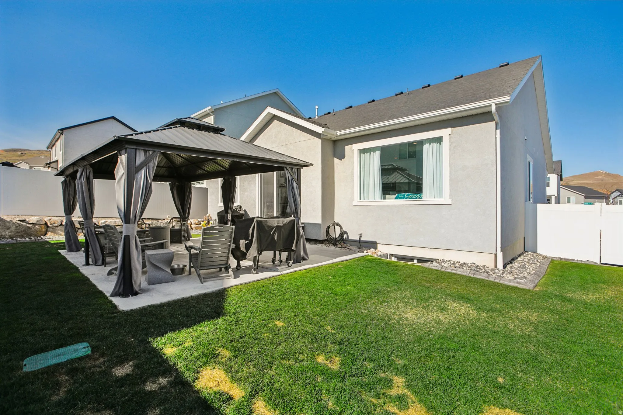 Back of house featuring a patio area, a gazebo, stucco siding, a fenced backyard, and an outdoor living space