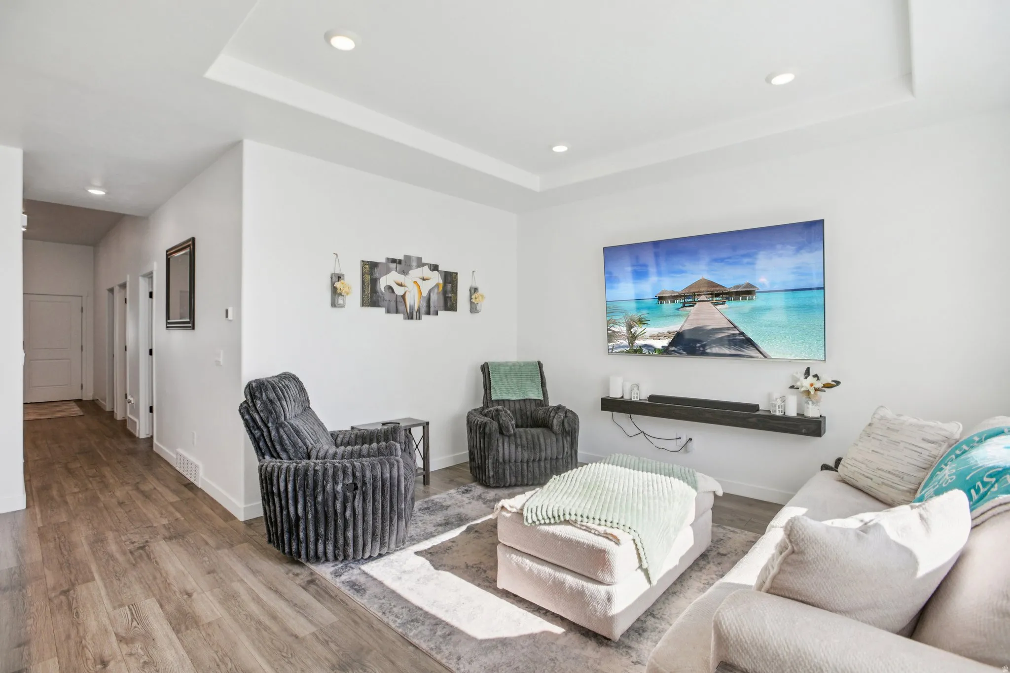 Living room featuring a raised ceiling, wood finished floors, and recessed lighting