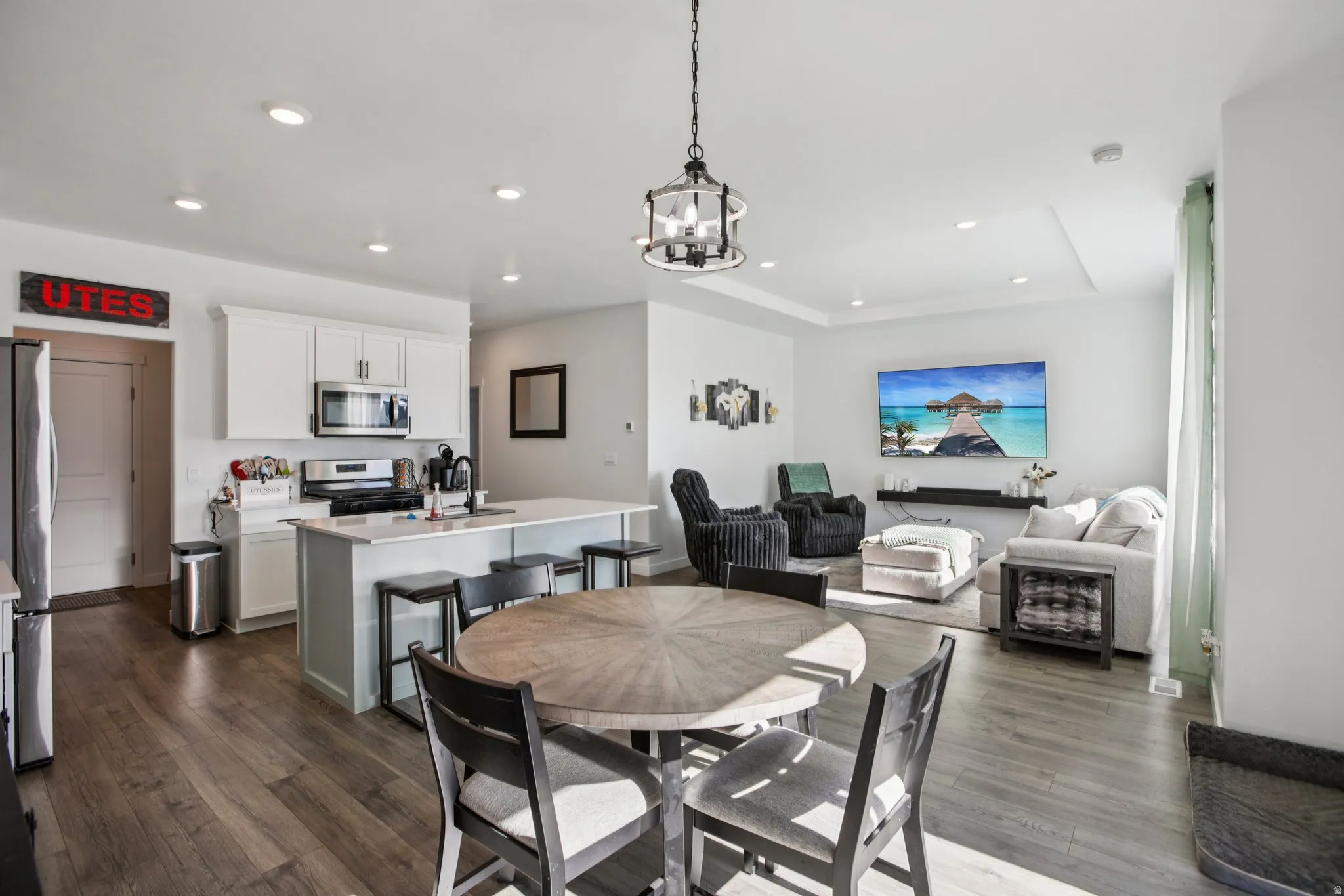 Dining area with a tray ceiling, dark wood-style floors, and hanging lights