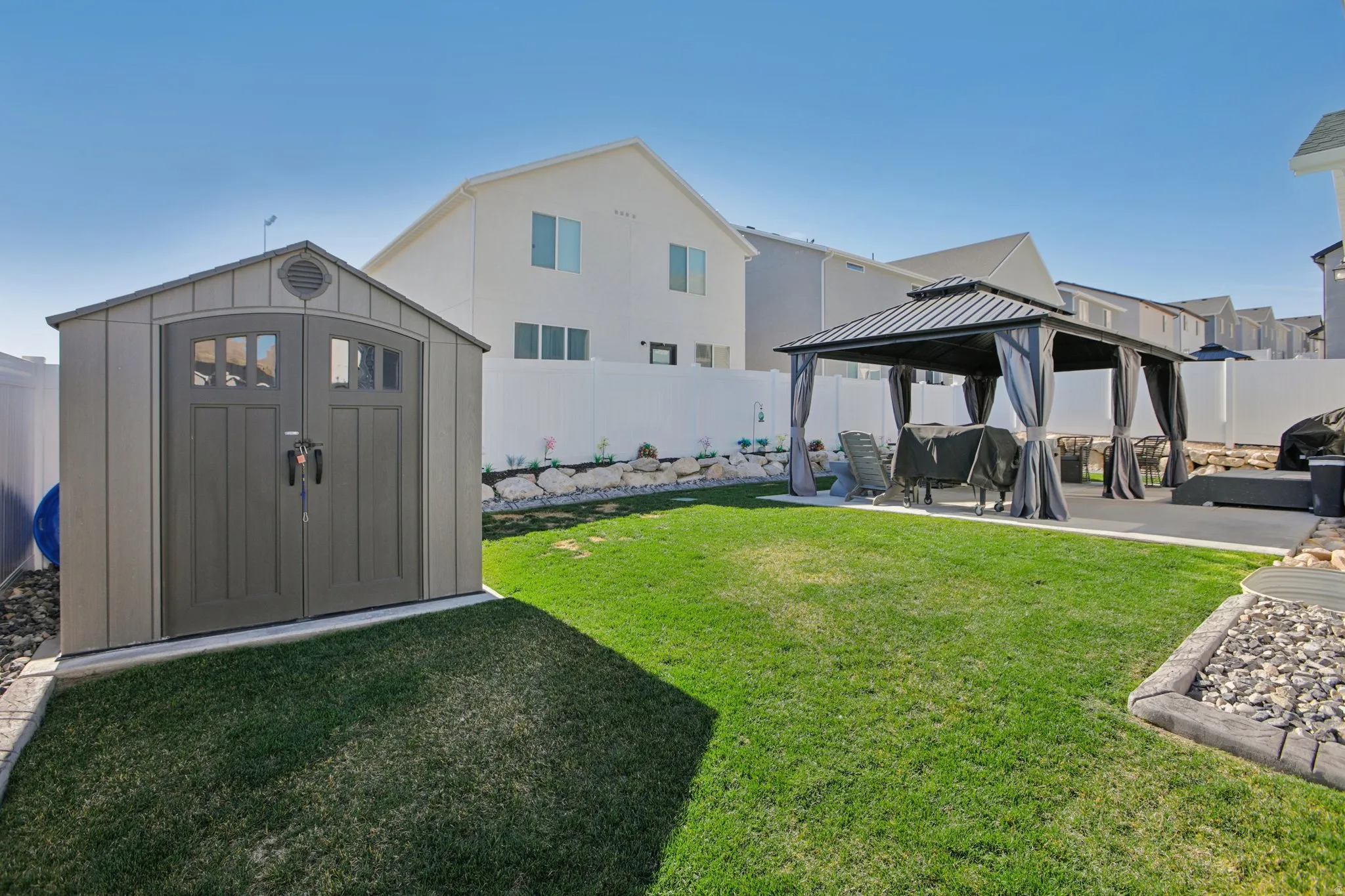 Fenced backyard with a patio area, a gazebo, and a storage unit