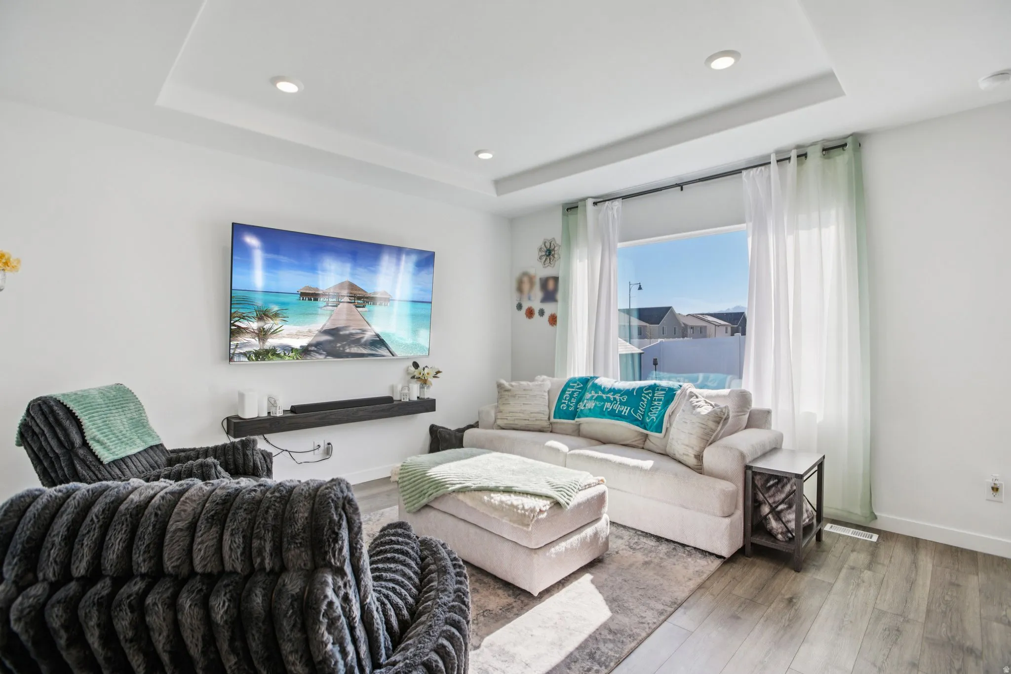 Living area featuring wood finished floors, recessed lighting, and a raised ceiling
