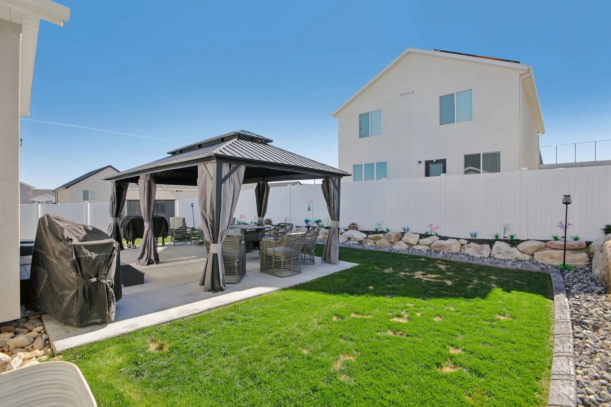 Fenced backyard featuring a gazebo and a patio