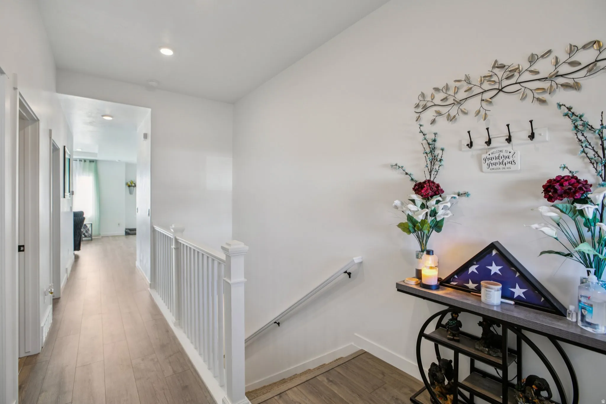 Hallway with wood finished floors, an upstairs landing, and recessed lighting