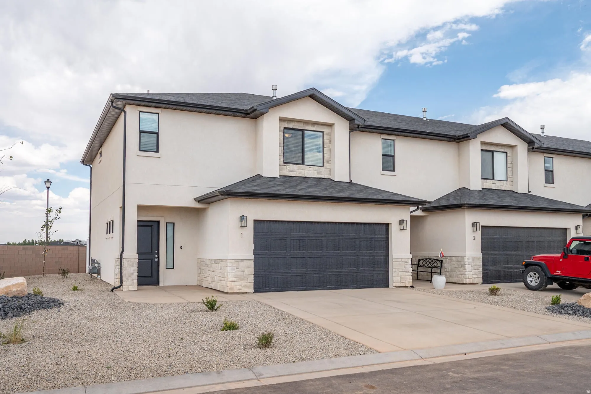 View of front of property with stone siding, stucco siding, concrete driveway, and an attached garage