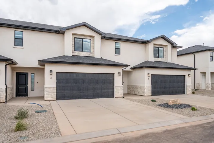 View of front of home featuring stone siding, stucco siding, concrete driveway, and a garage
