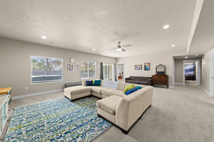 Living room with light carpet, ceiling fan, a textured ceiling, and recessed lighting