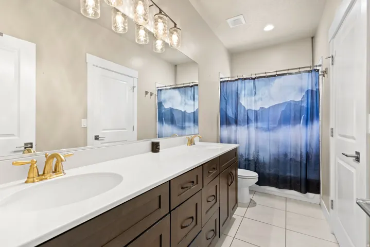 Full bathroom featuring double vanity and light tile patterned flooring