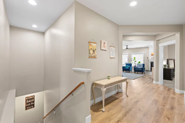 Corridor with light wood finished floors, recessed lighting, and an upstairs landing