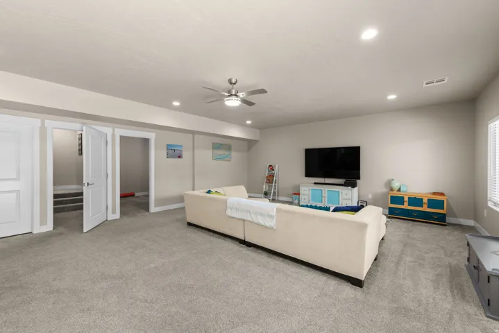 Living room featuring ceiling fan, light carpet, and recessed lighting