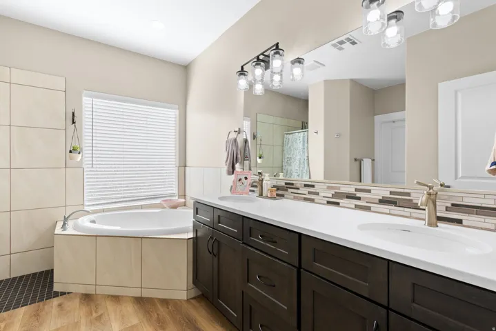 Bathroom with double vanity, a shower stall, a bath, and light wood finished floors