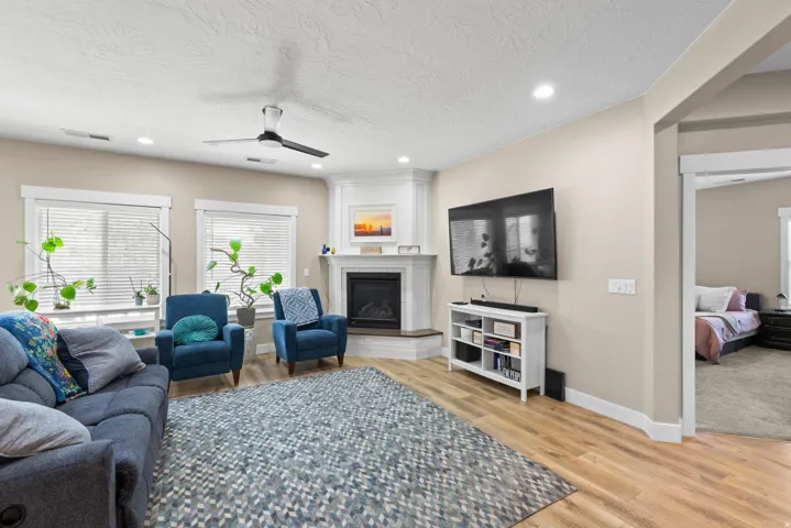 Living area with ceiling fan, light wood-type flooring, a fireplace, recessed lighting, and a textured ceiling