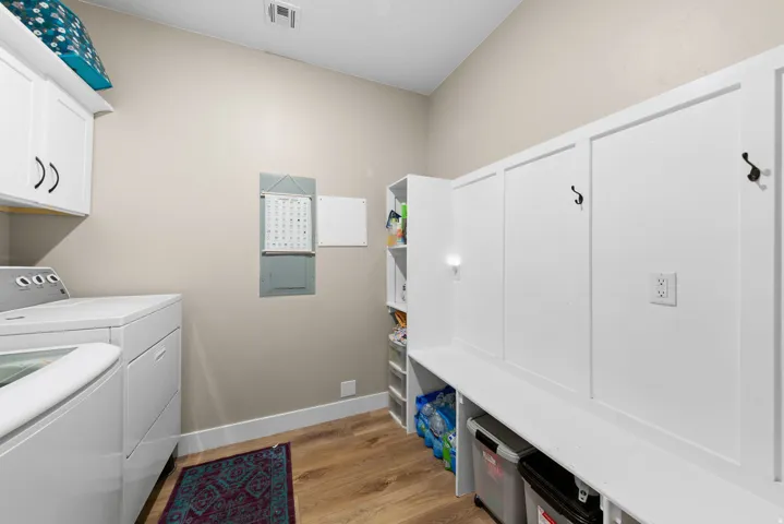 Laundry area with light wood-style flooring, washer and dryer, cabinet space, and electric panel