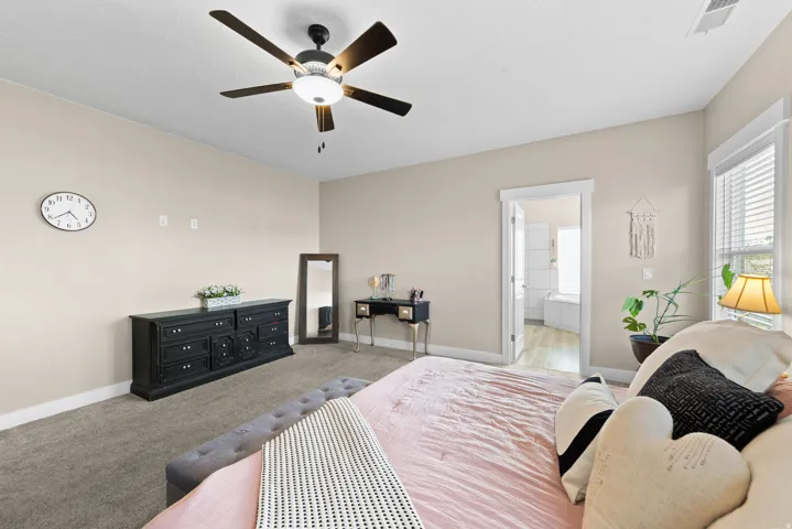 Bedroom with carpet flooring, a ceiling fan, and ensuite bathroom