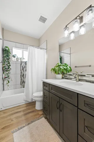Bathroom with light wood-type flooring, vanity, and shower / bath combo