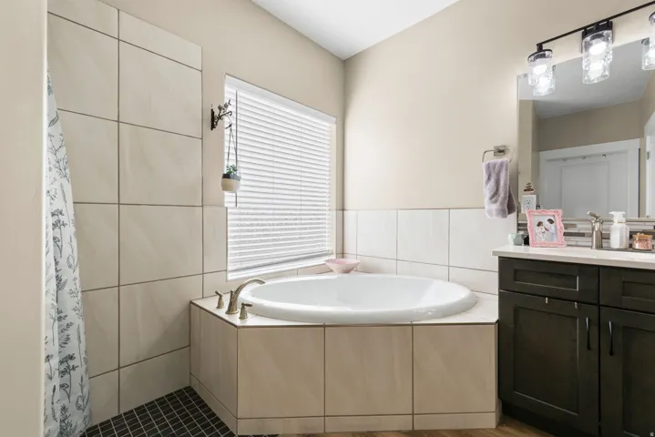 Bathroom with a bath, a tile shower, vanity, and tile walls