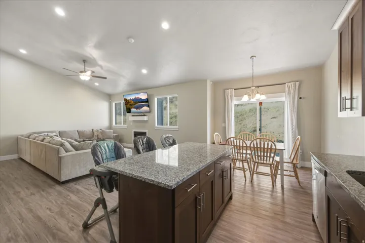 Kitchen featuring a kitchen island, dark wood finish cabinets, light stone countertops, and lofted ceiling