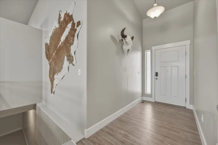 Front door entryway with wood finished floors and vaulted ceiling