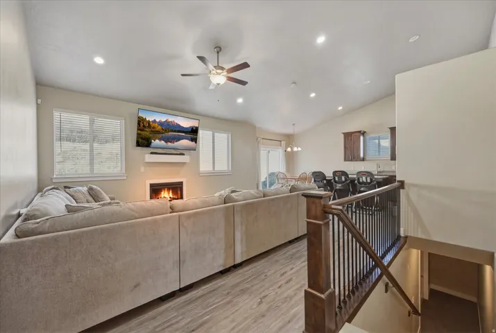 Living room with ceiling fan, light wood-style flooring, lofted ceiling, recessed lighting, and fireplace
