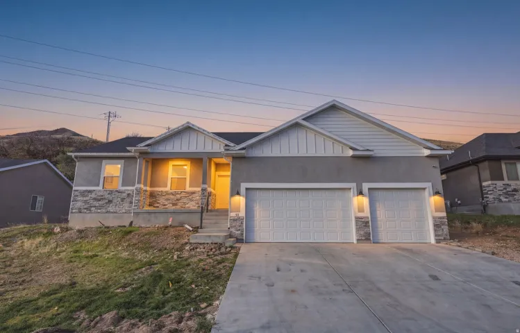Craftsman-style home with stone siding, a garage, concrete driveway, covered porch, and board and batten siding
