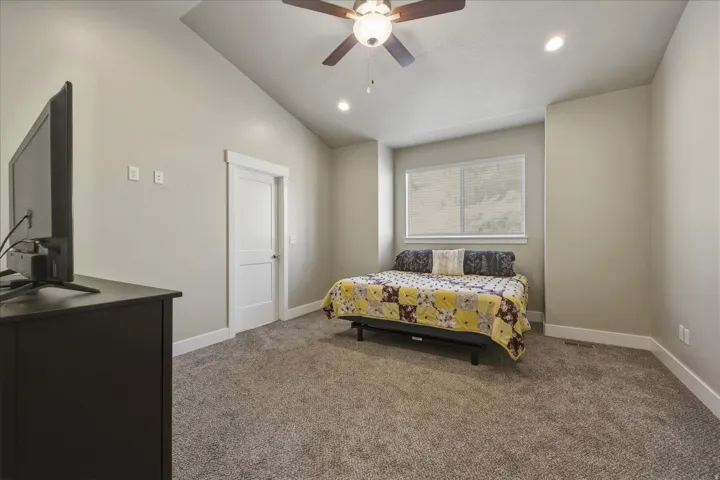 Carpeted bedroom with lofted ceiling, a ceiling fan, and recessed lighting