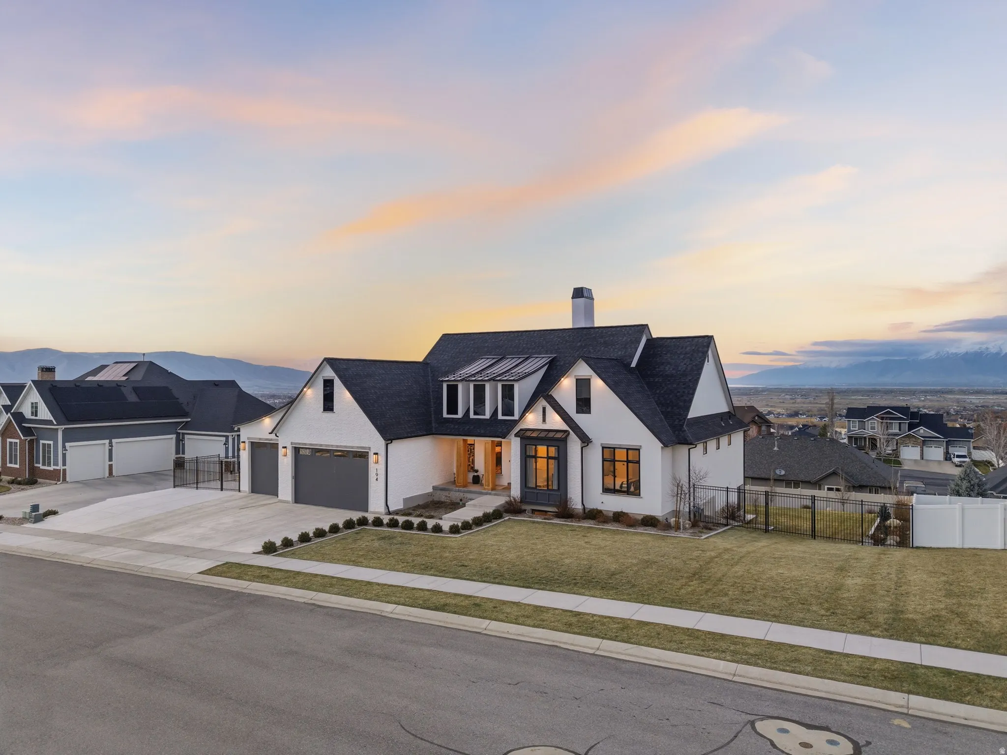 Modern farmhouse style home with a chimney, a residential view, driveway, and stucco siding