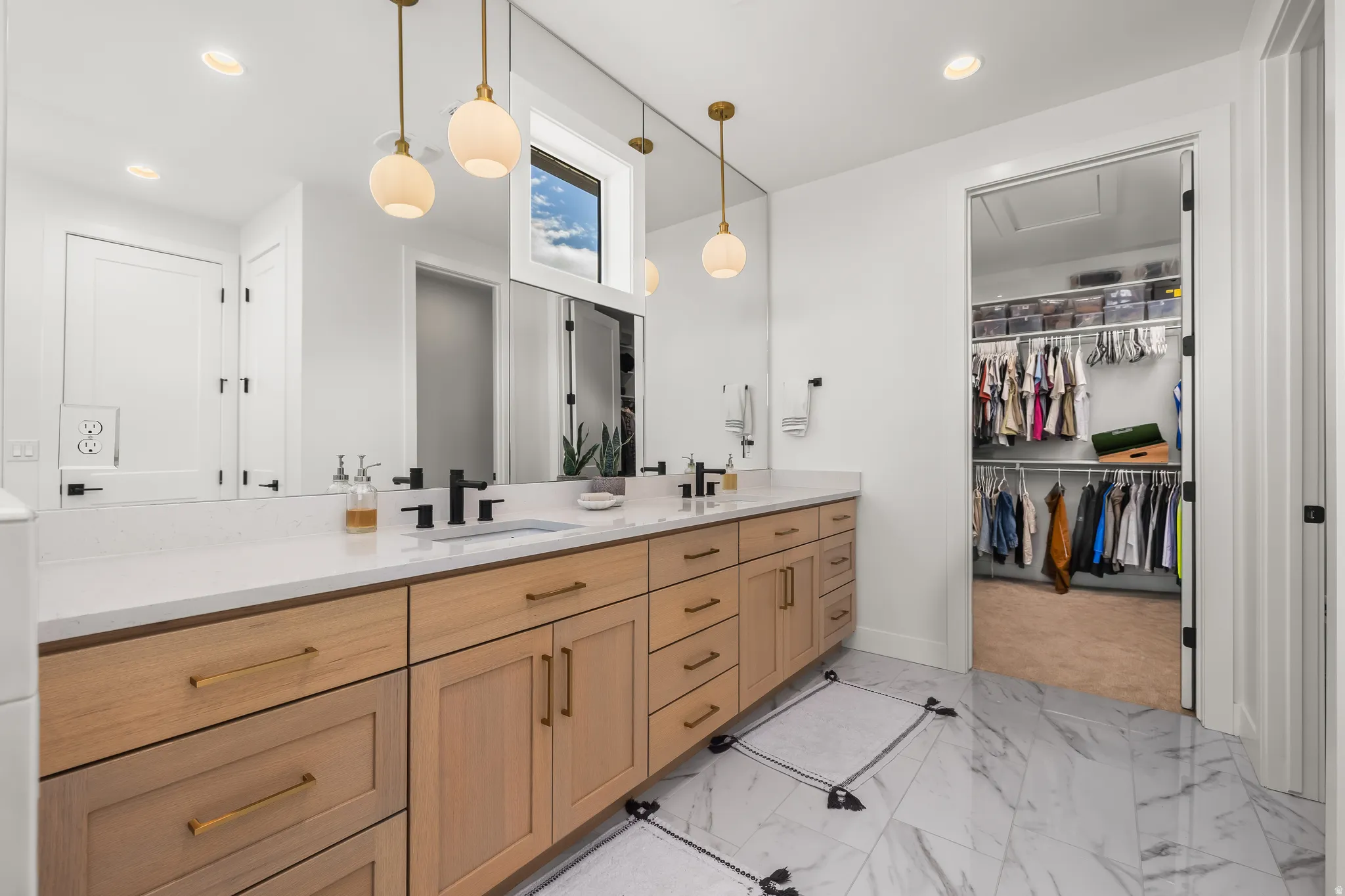 Full bath with double vanity, a spacious closet, light marble finish floors, and recessed lighting