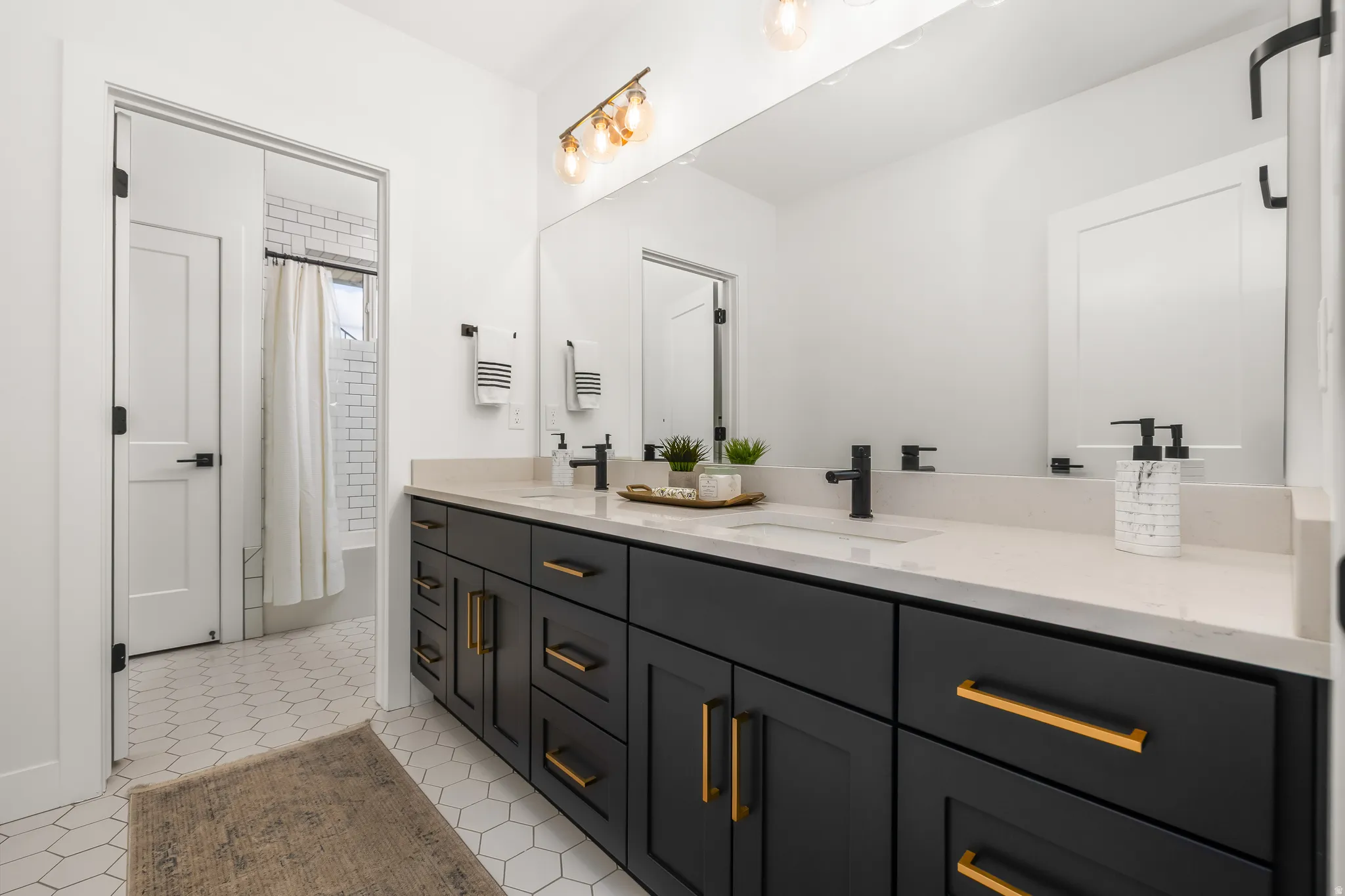 Full bath with double vanity, shower / tub combo with curtain, and light tile patterned floors