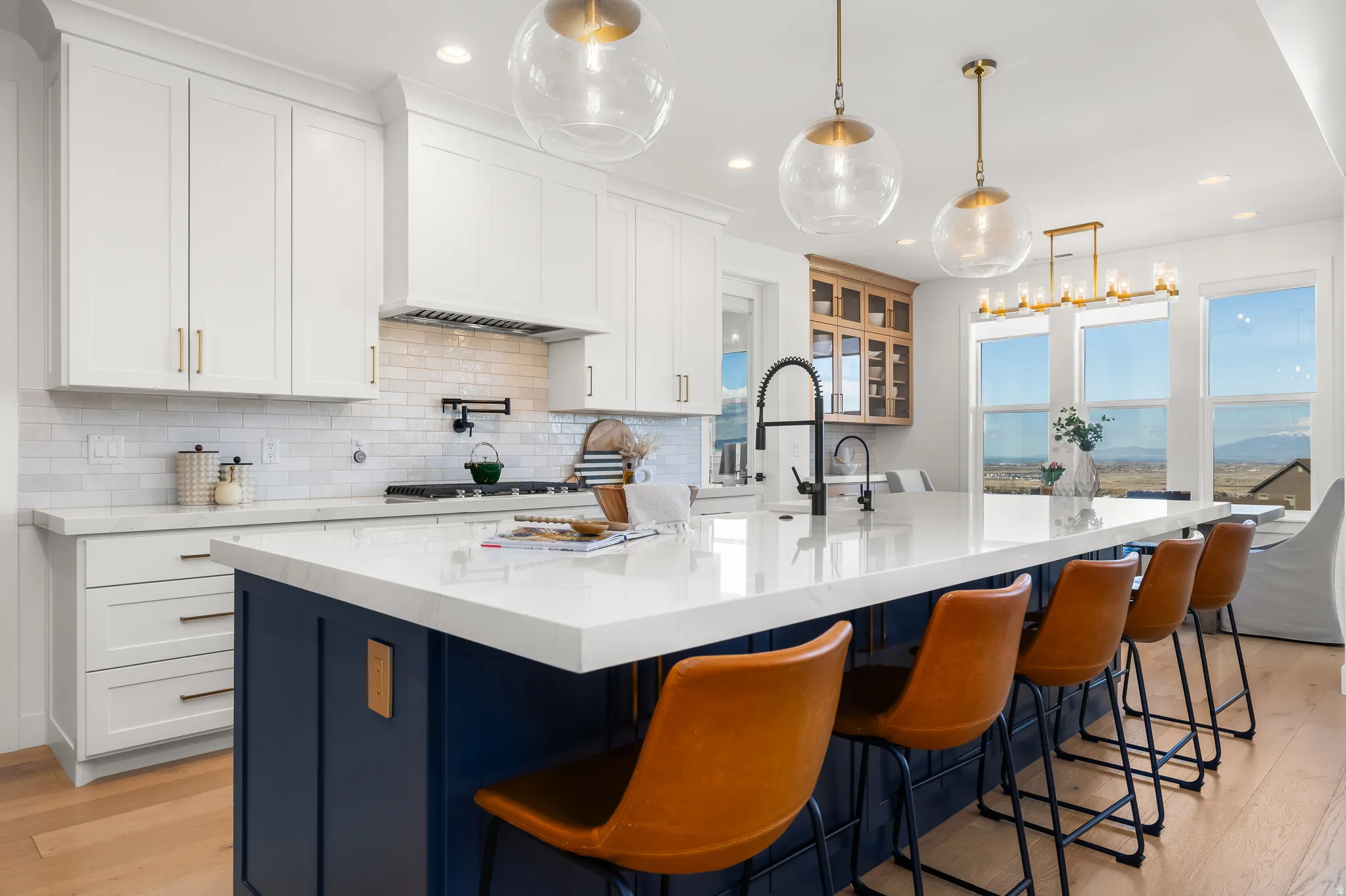Dual tone kitchen with light wood-style flooring, a kitchen breakfast bar, light stone countertops, a large island, and dual tone cabinets