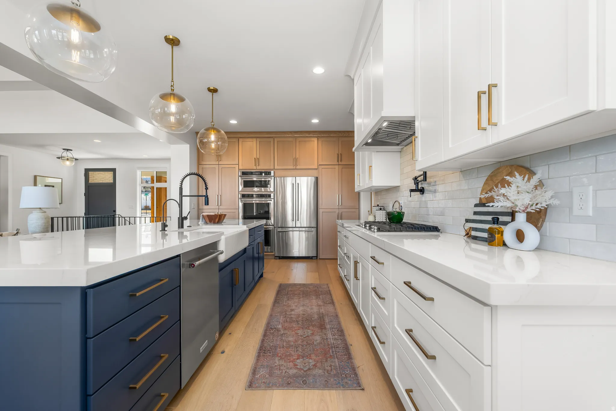 Kitchen with dual tone cabinetry, light stone counters, stainless steel appliances, light wood-style flooring, and a spacious island