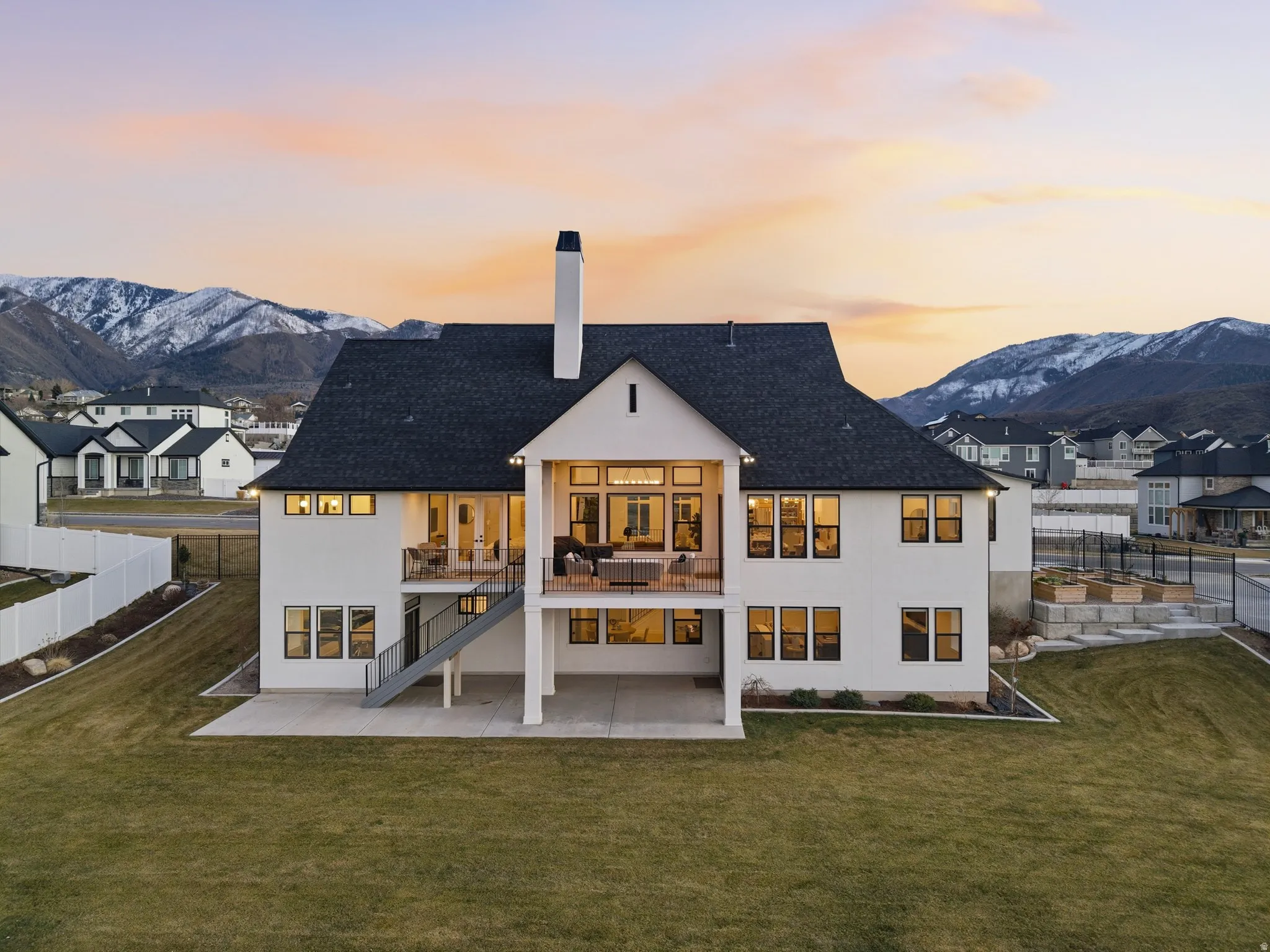 Back of property at dusk with a chimney, a patio area, a mountain view, and stucco siding